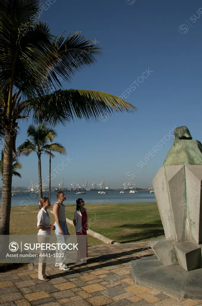 Tourists looking at statue of Bartholomew Diaz on the Victoria Embankment with the harbour in the background. Durban. KwaZulu Natal. South Africa.