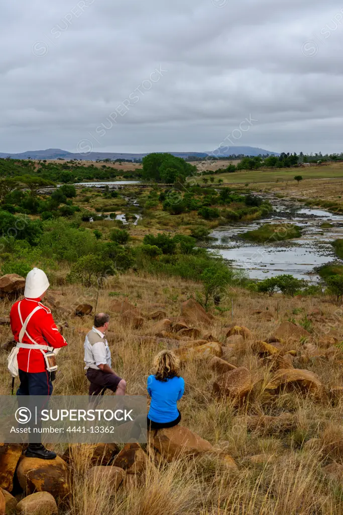 A British soldier and tourists looking at Rorke's (Rorkes) Drift accross the Buffalo River. KwaZulu Natal. South Africa