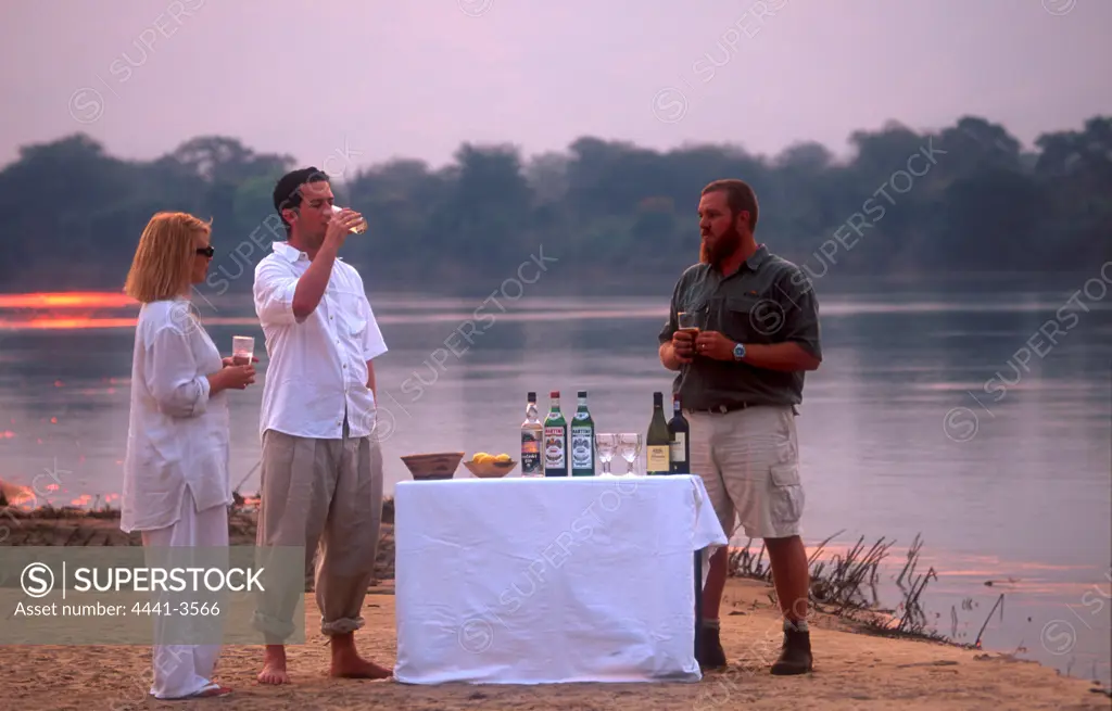 Guests Having drinks on sand bank in Zambezi River. Kiubo Lodge. Lower Zambezi National Park. Zambia