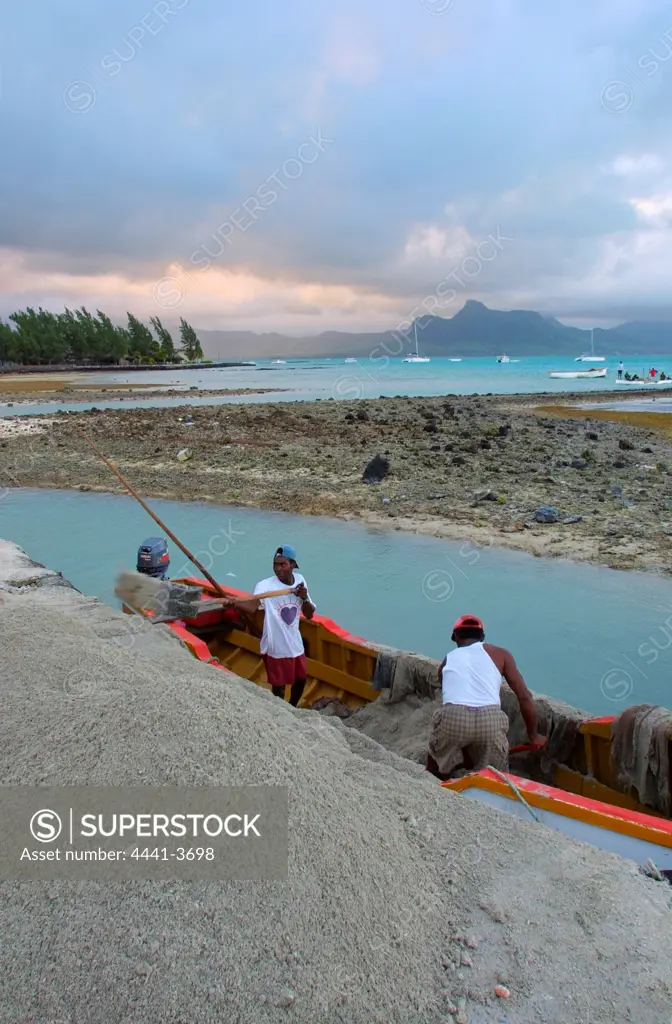 Men off loading sand dug from shallows and used for building. Mahebourg.  Mauritius