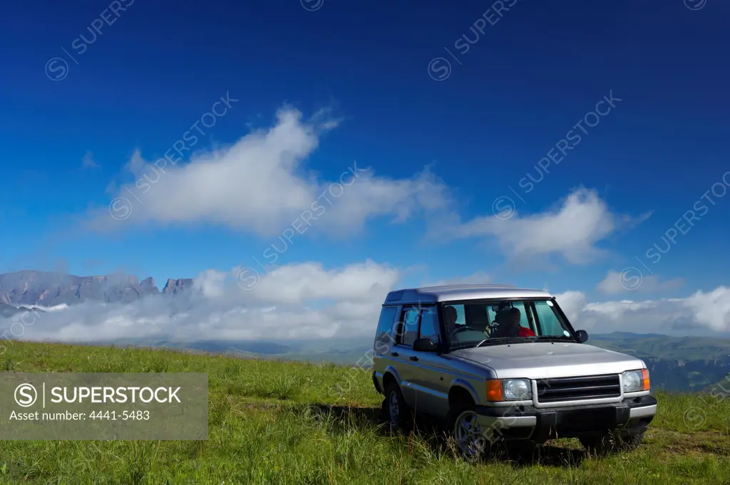 Couple and their off road vehicle in fromt of the Drakensberg at Giants Castle. Ukhahlamba Drakensberg Park. KwaZulu Natal. South Africa