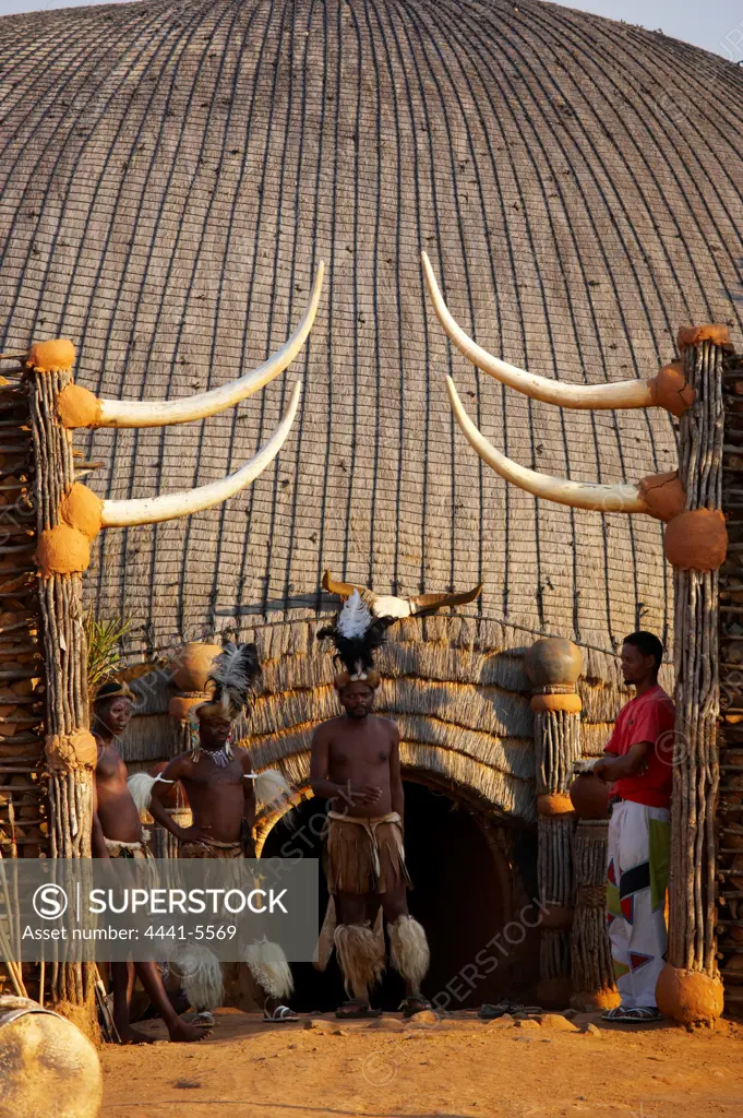 Zulu warriors standing outside a traditional grass hut. Shakaland. Eshowe. KwaZulu Natal. South Africa