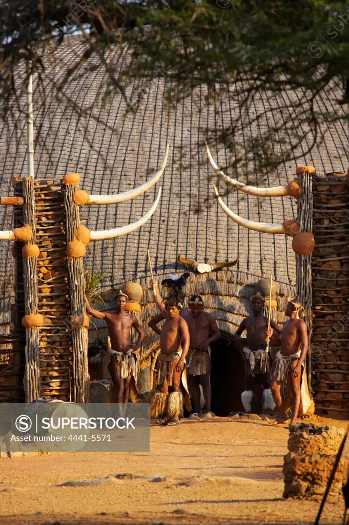 Zulu warriors standing outside a traditional grass hut. Shakaland. Eshowe. KwaZulu Natal. South Africa