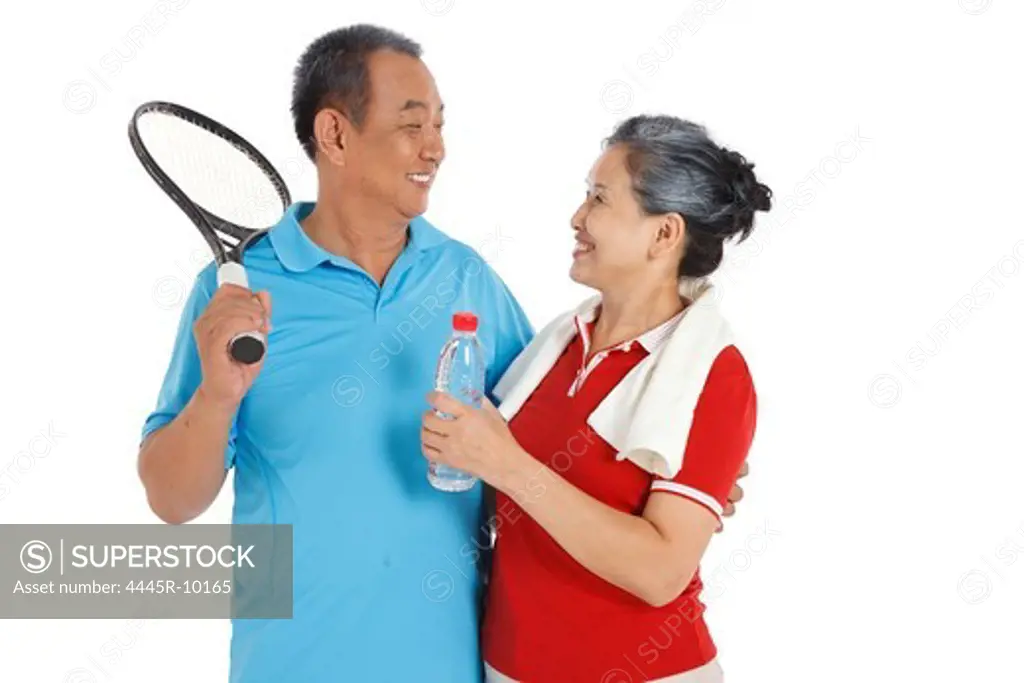 Senior couple holding racket and water