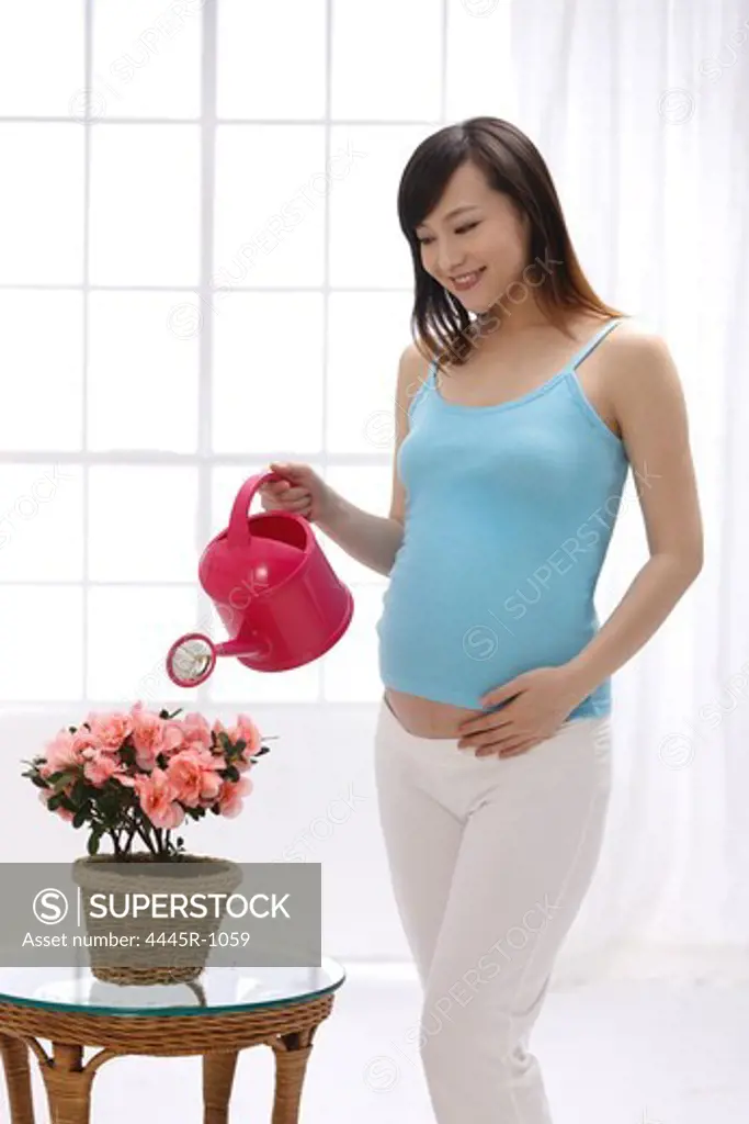 Pregnant woman watering flowers