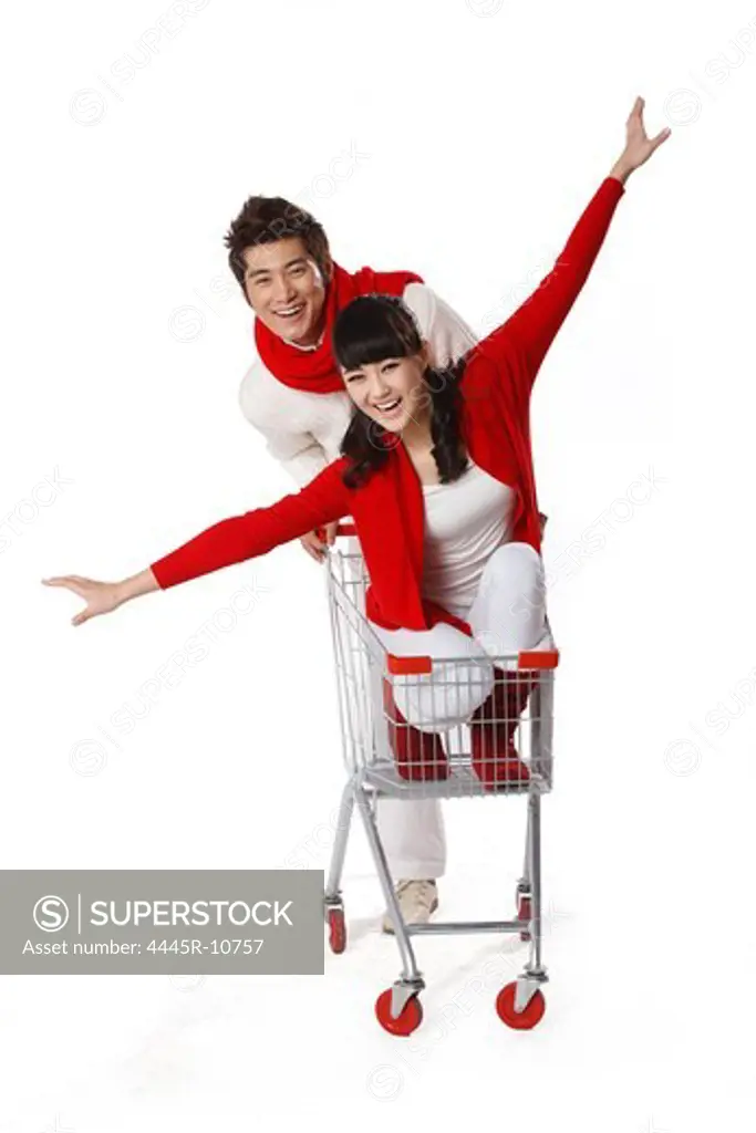 Young man pushing young woman in shopping cart