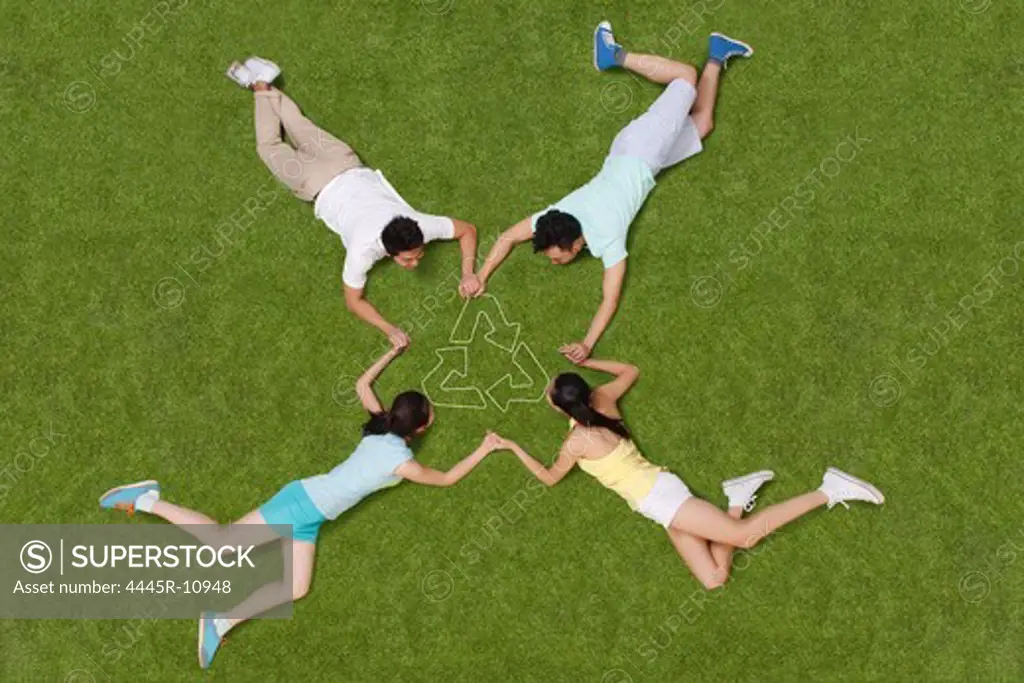 Young people lying on grass hand in hand