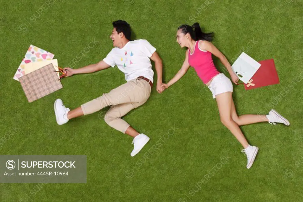Young couple holding shopping bags on grass