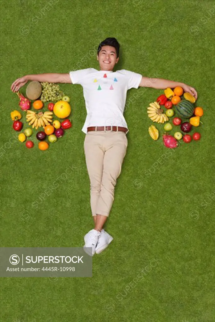 Young man lying on grass with fruits