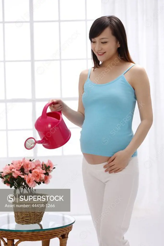 Pregnant woman watering flowers