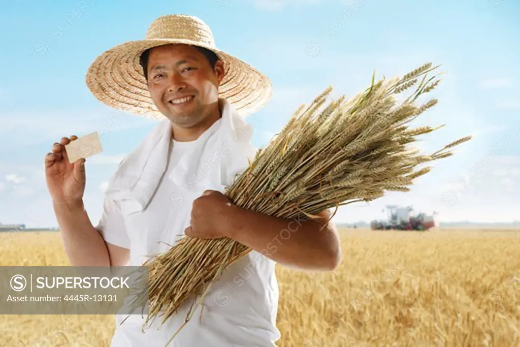 Farmer holding card and wheat in field