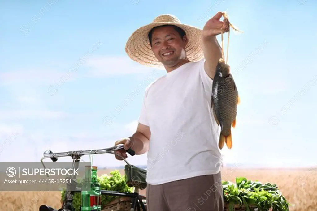 farmer holding fish with bicycle and vegetables