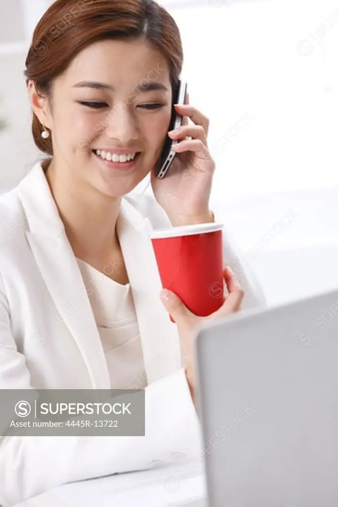 Young business lady drinking coffee and making phone call