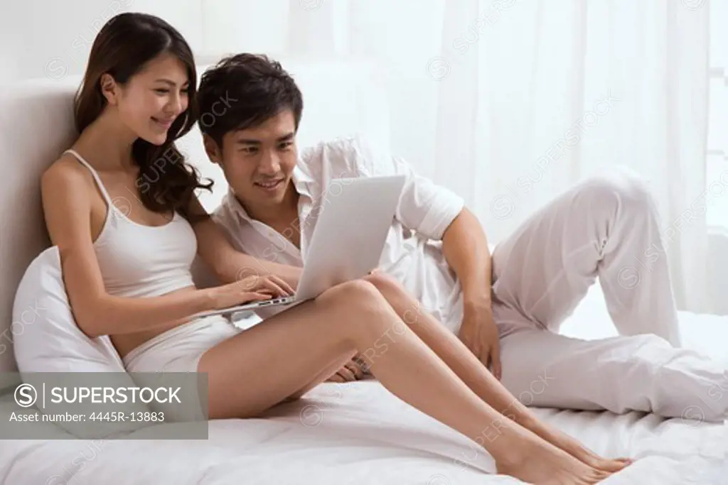 Young couple using laptop on bed