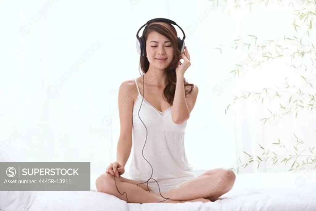 Young lady listening to music on bed