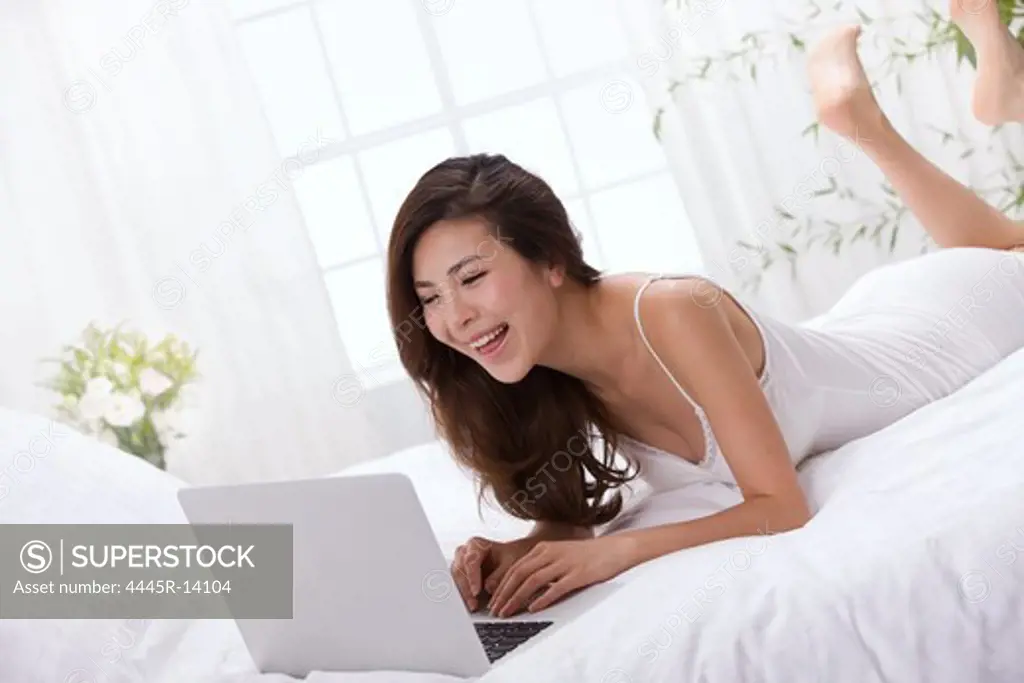 Young lady using laptop on bed