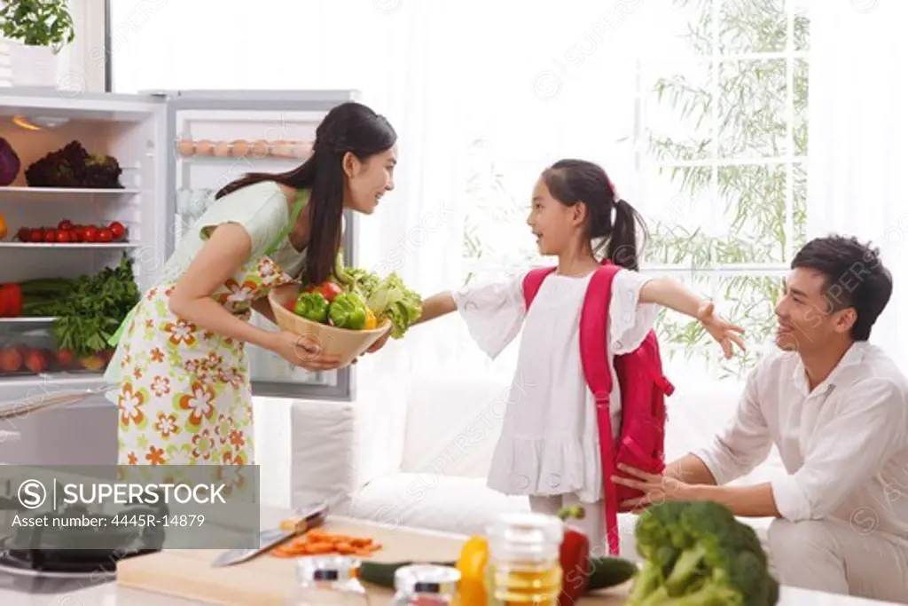 Family holding vegetables in kitchen