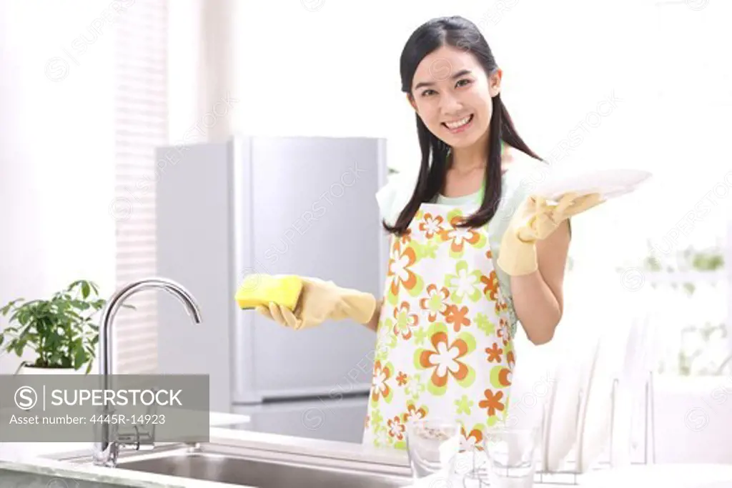 Young woman washing dishes in kitchen