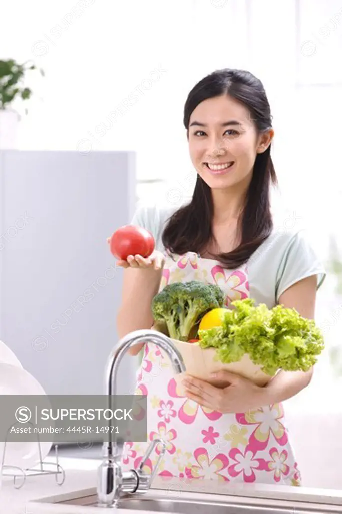 Young woman holding vegetables in kitchen