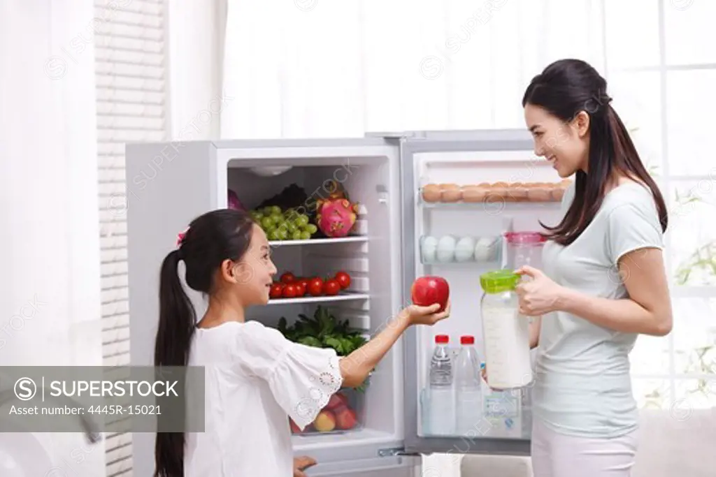Mother and daughter holding apple in kitchen