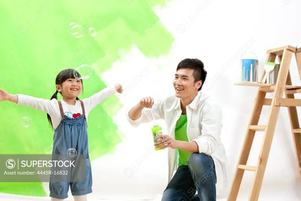 Happy father and daughter blowing bubbles