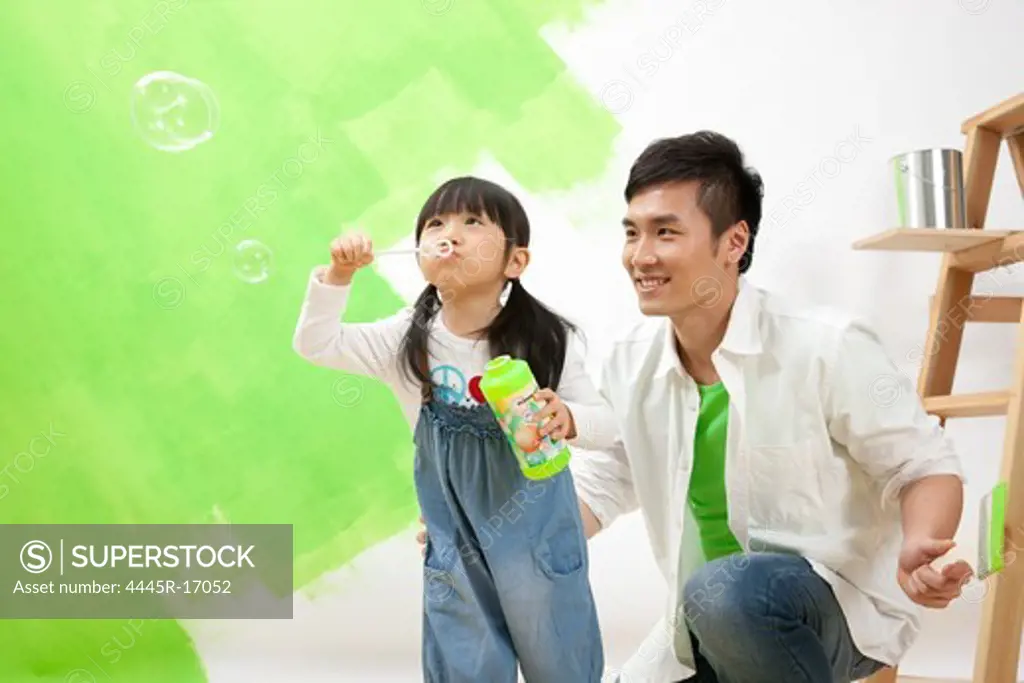 Happy father and daughter blowing bubbles