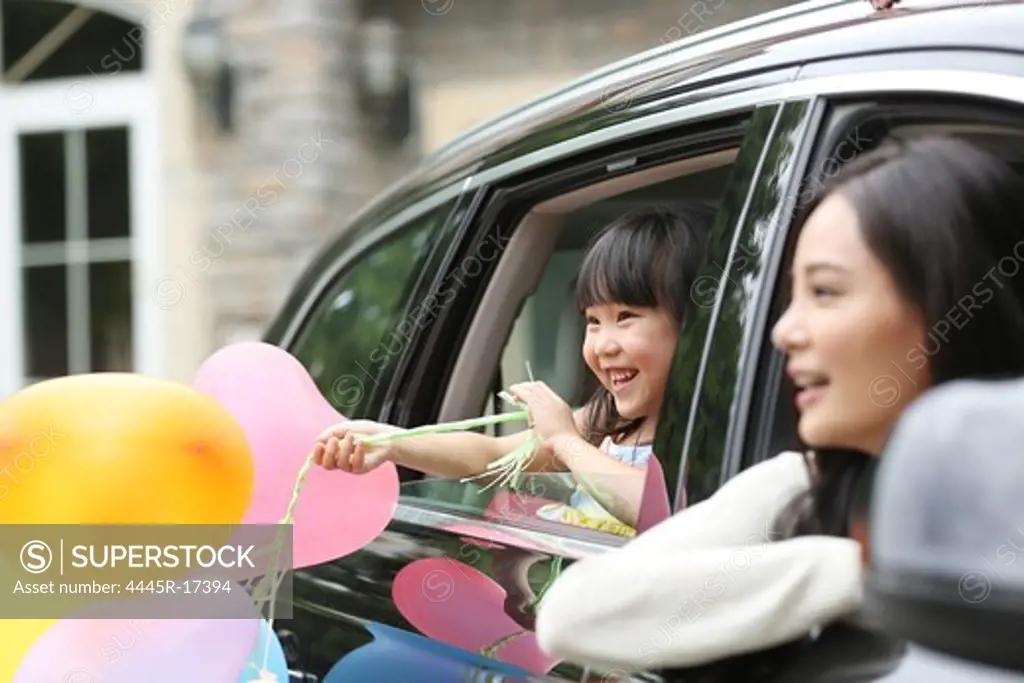Happy little girl and her mother sitting in the car