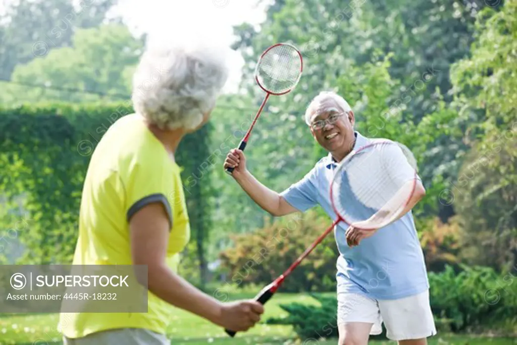 Happy elderly couple playing badminton