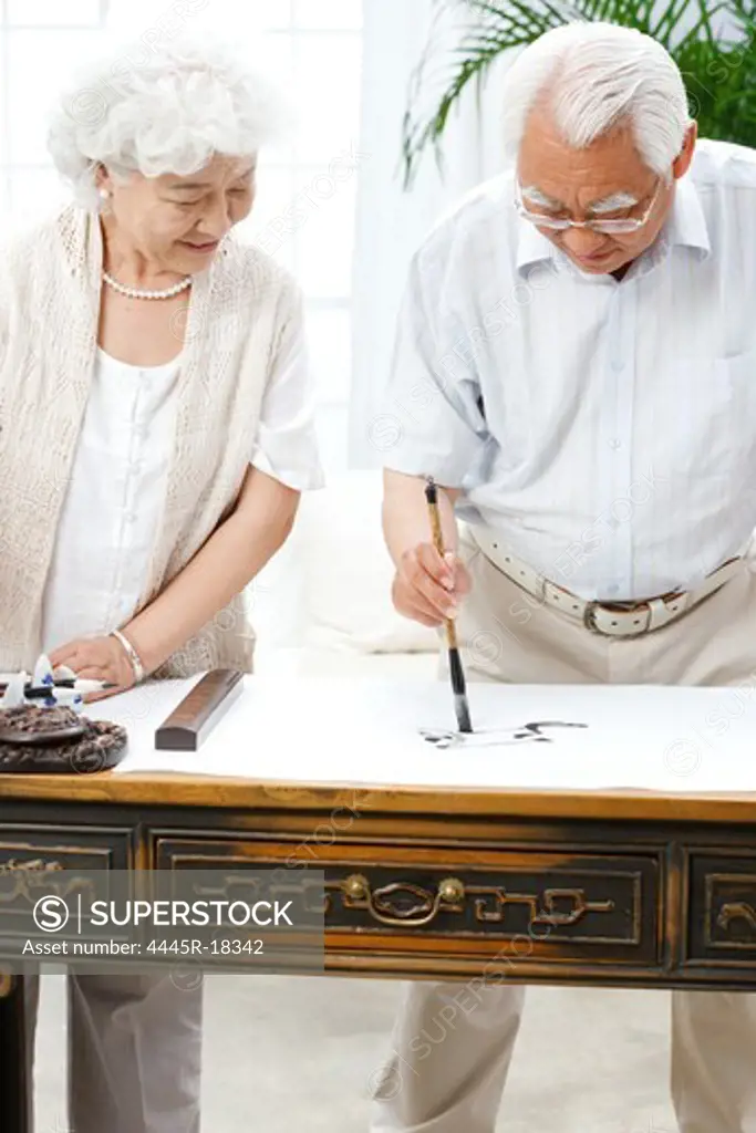 Happy elderly couple practicing calligraphy