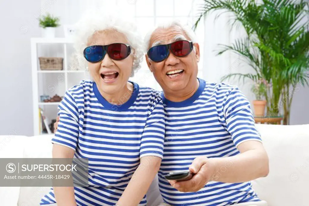 Happy elderly couple watching 3D TV