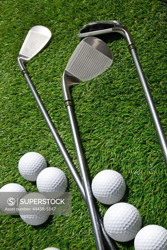 Golf balls and clubs on grass