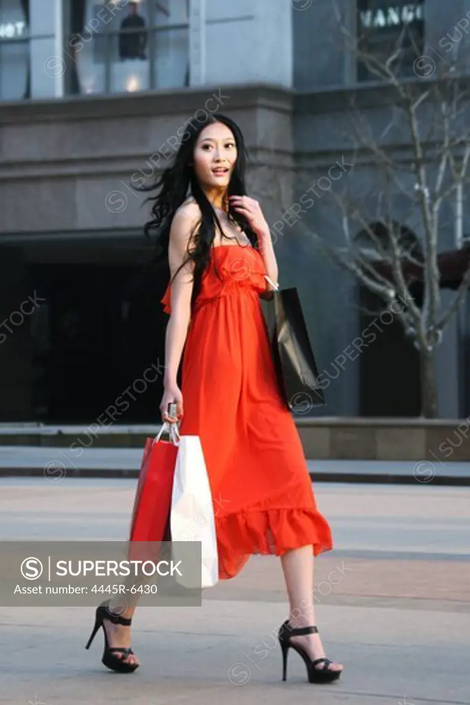Woman carring shopping bags walking along street
