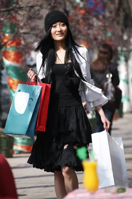 Woman carring shopping bags walking along street