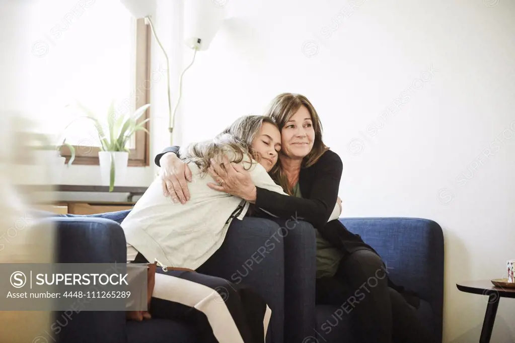 Mother and daughter embracing while sitting at wellness center