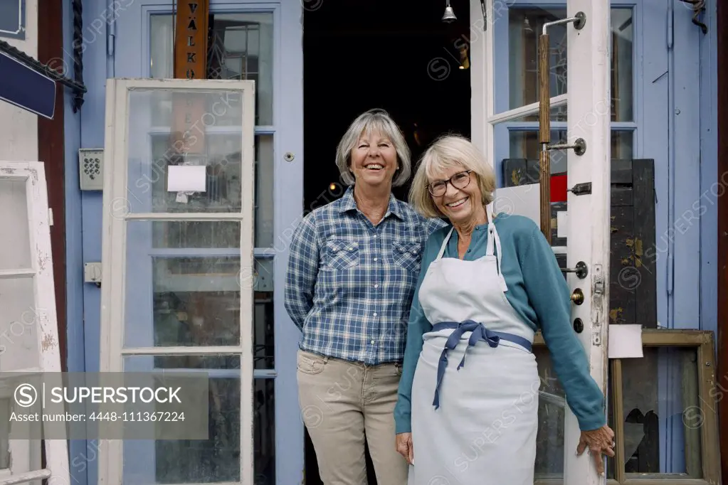 Portrait of cheerful female owners standing at store entrance