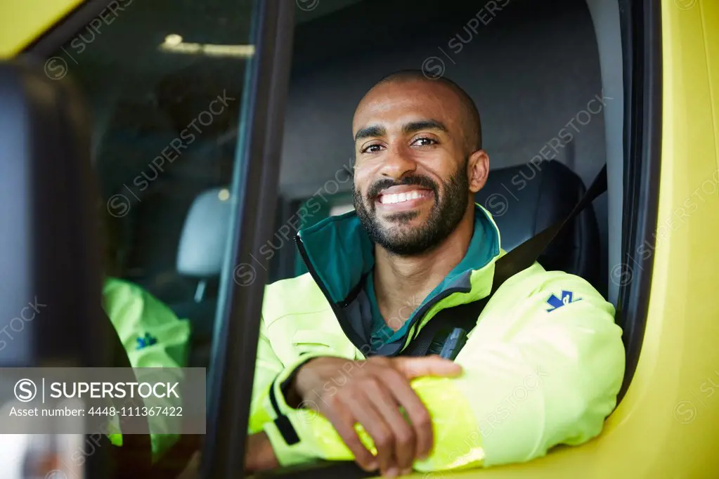 Portrait of smiling male paramedic in ambulance at parking lot