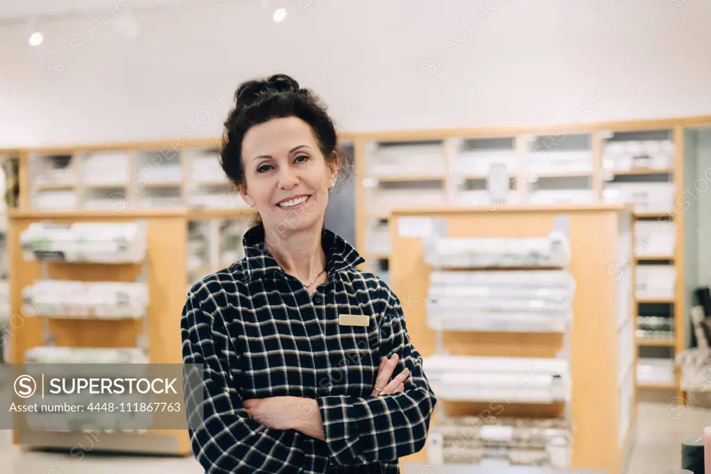 Portrait of smiling saleswoman with arms crossed standing in store