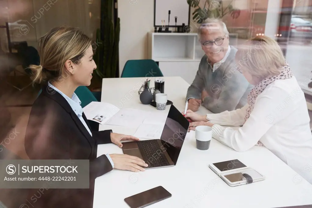 Female estate agent discussing with senior couple over property documents in office