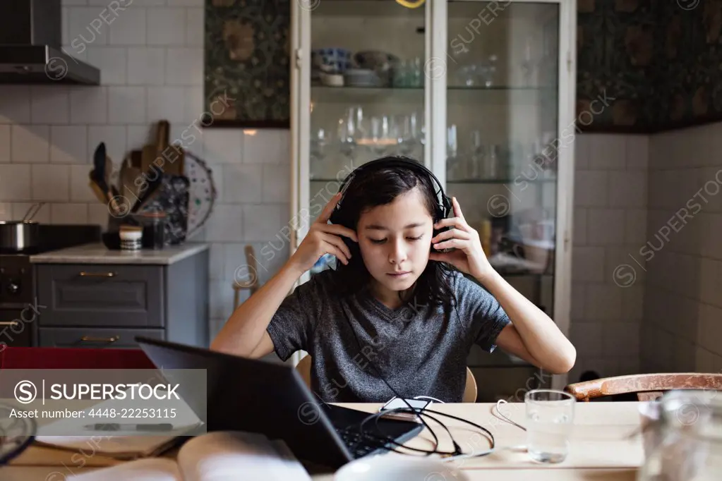 Boy using headphones while doing homework at home