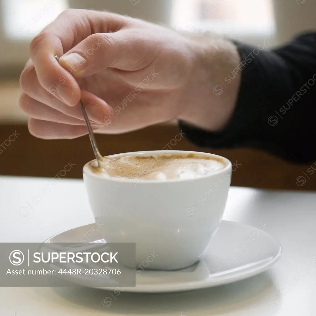 Man stirring in a coffee cup