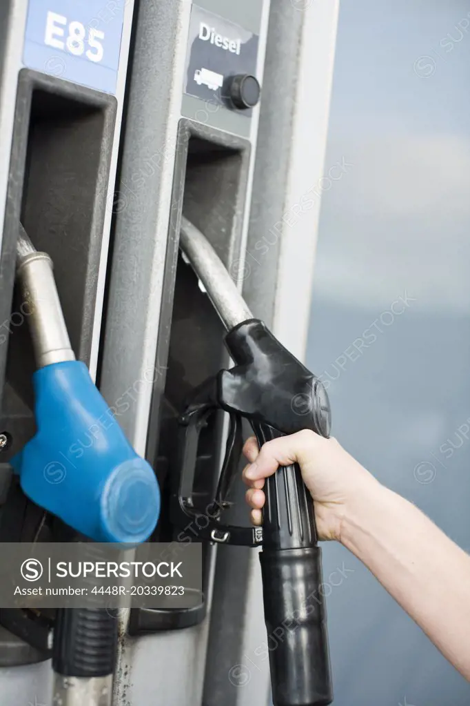 Female hand lifting leaded petrol pump