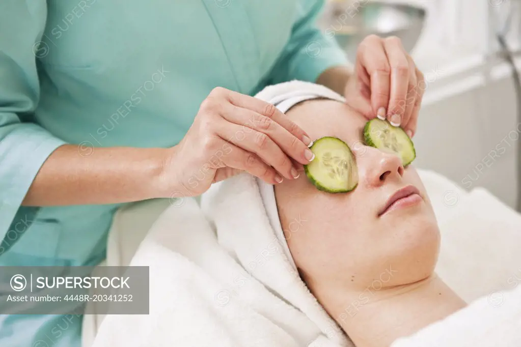 Midsection of beautician giving a beauty treatment to young woman in spa