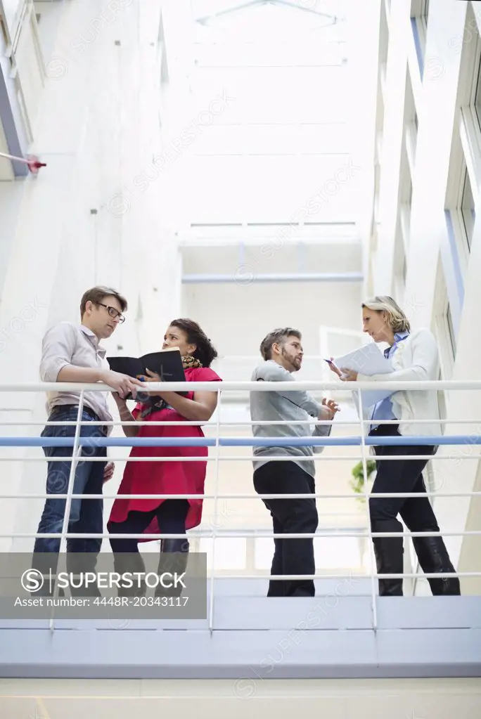 Low angle view of business people discussing by railing