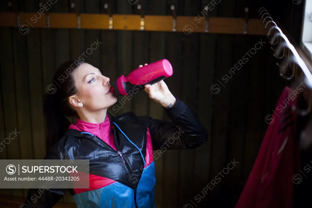 Mid adult woman drinking water in gym