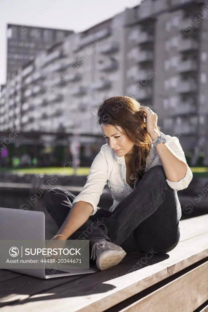 Businesswoman using laptop while sitting on boardwalk