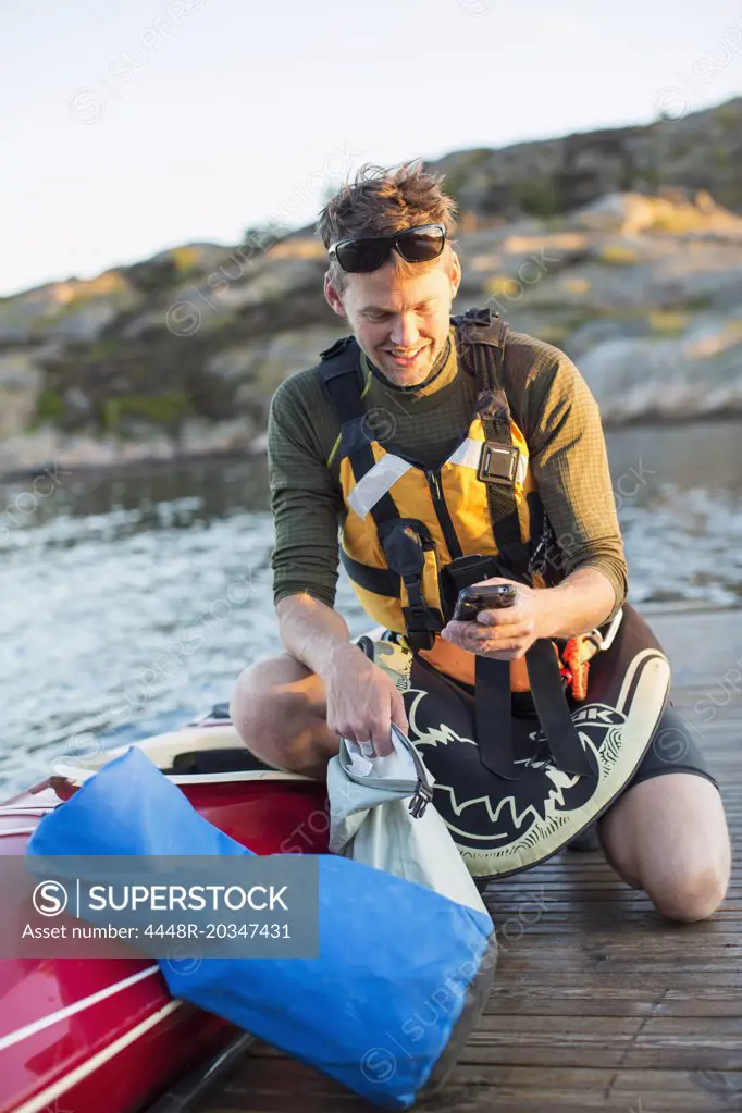 Man using mobile phone by kayak on pier