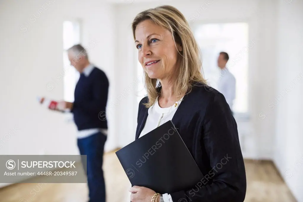 Thoughtful real estate agent with colleague and man in background at home