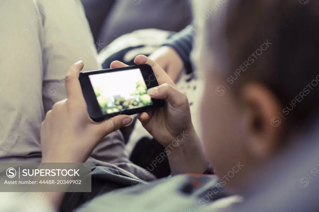 Boy playing game on mobile phone at home