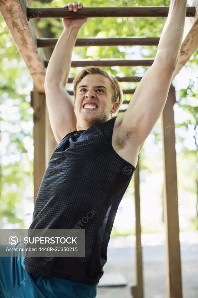 Dedicated man hanging on monkey bars at outdoor gym