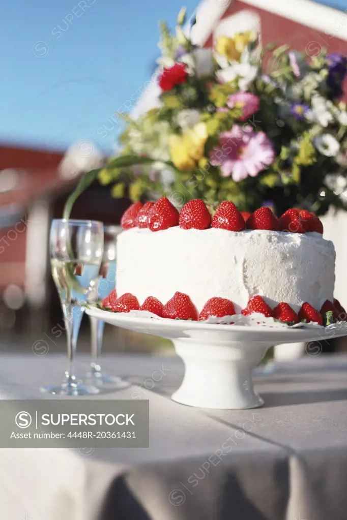 Close-up of vanilla cake with strawberries and champagne glass